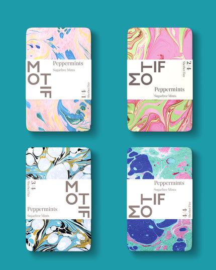 Four tins of Motif Sherbet Fizz candy with colorful and abstract marbled ink designs on the labels.