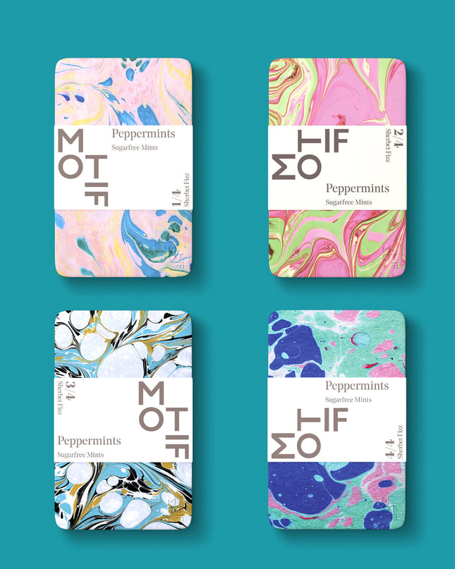 Four tins of Motif Sherbet Fizz candy with colorful and abstract marbled ink designs on the labels.