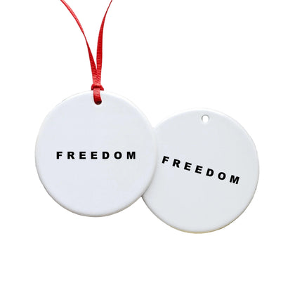 Two white heart-shaped ornaments with 'FREEDOM' text on a wooden surface with string lights and greenery.