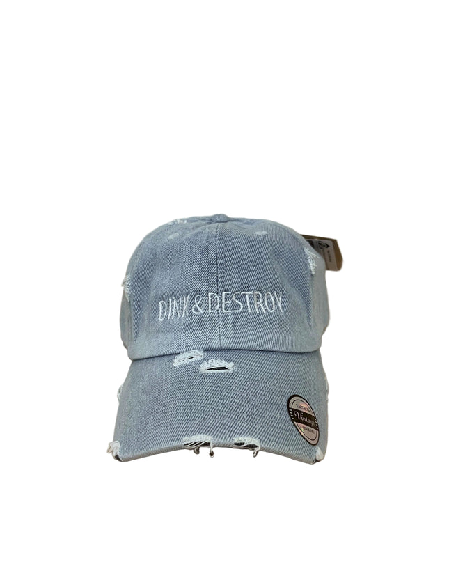 Blue distressed cap with 'Dink & Destroy' text on a wooden surface.