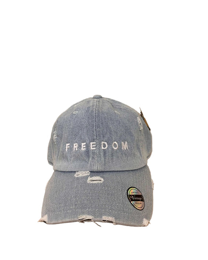 Blue denim cap with 'FREEDOM' text on a wooden surface