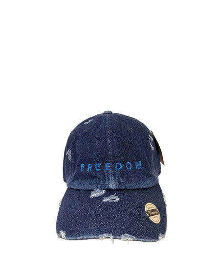 Blue denim cap with 'FREEDOM' embroidery on a wooden surface